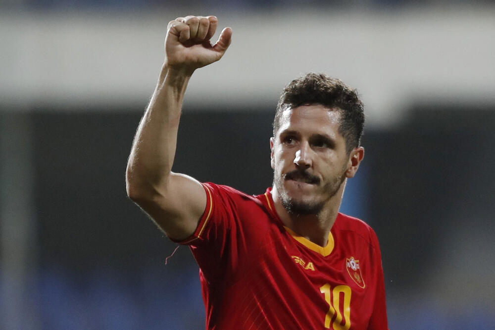 Stevan Jovetic in Montenegro jersey with his armed lifed above the head